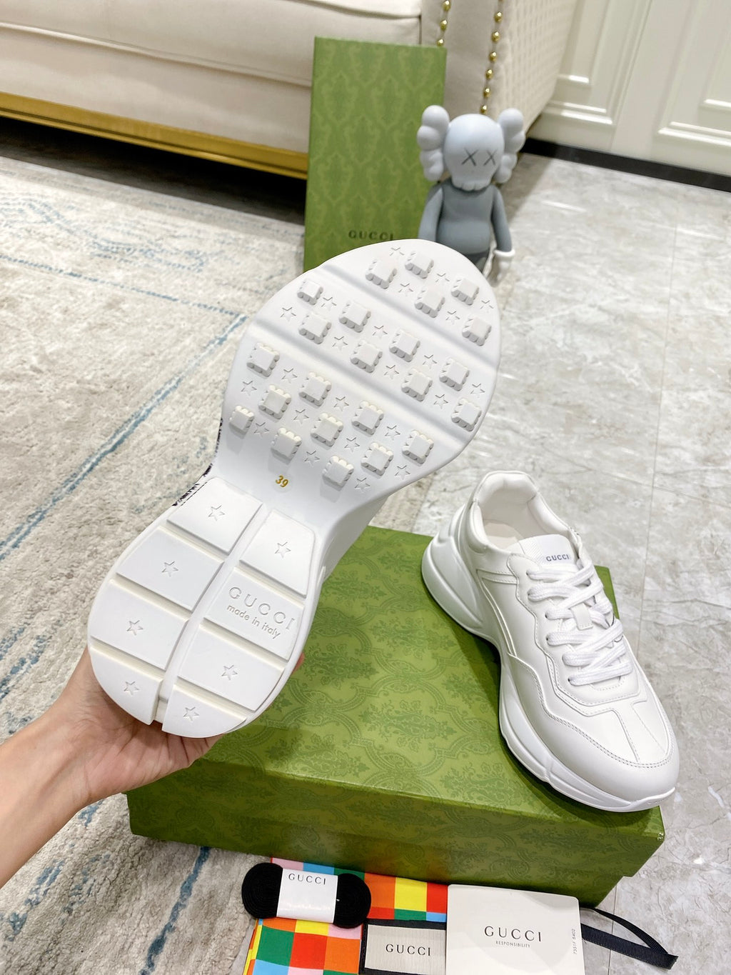 White Gucci unisex sneakers with textured tread sole visible; lace-up uppers.