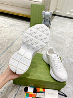 White Gucci unisex sneakers with textured tread sole visible; lace-up uppers.