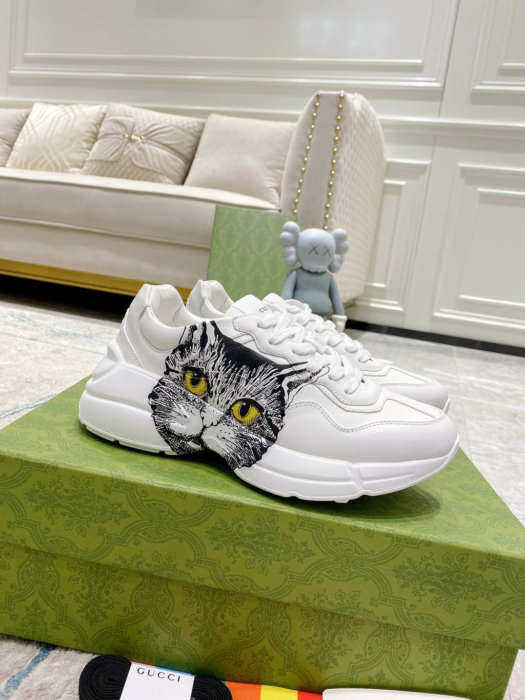 White Gucci unisex sneakers with cat face graphic on side, lace-up front.