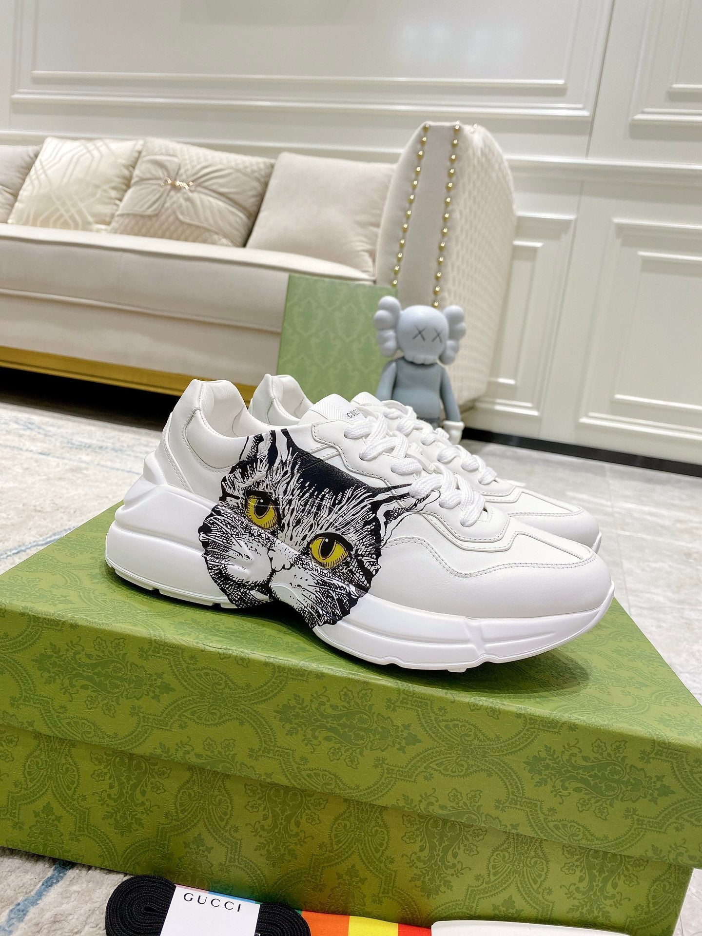 White Gucci unisex sneakers with cat face graphic on side, lace-up front.