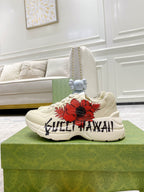 Gucci unisex sneakers, side view of white pair with red flower patch and black text