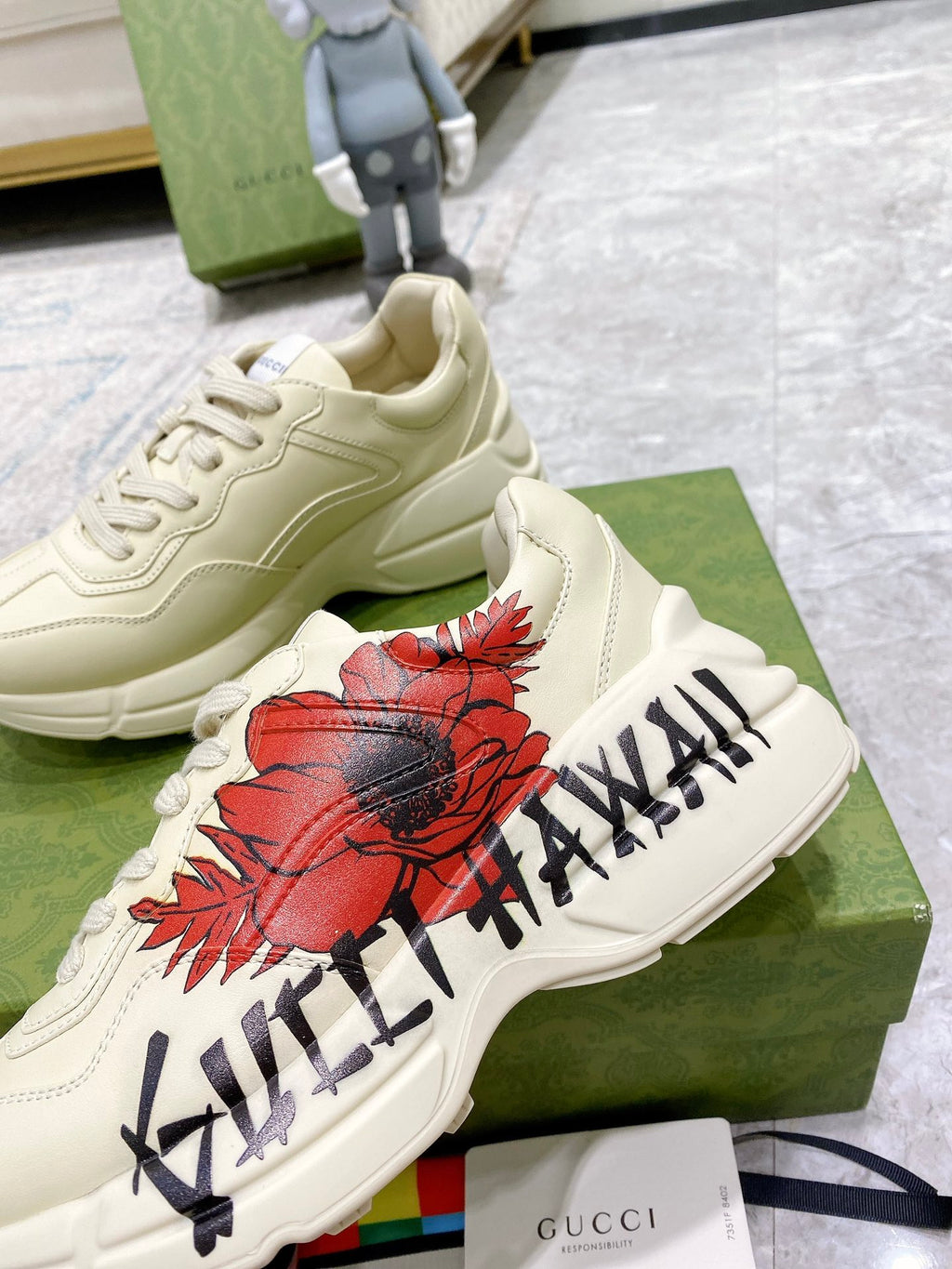 Gucci unisex sneakers, close-up of white shoes with red floral patch and black lettering