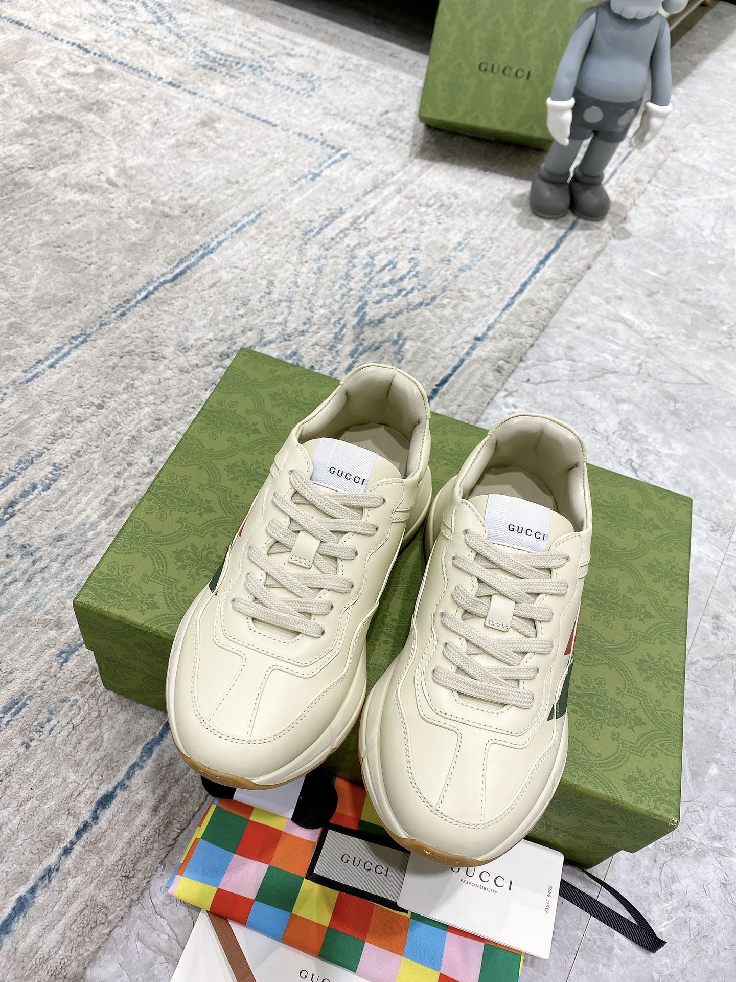 Pair of unisex white lace-up sneakers with multicolor stripe detail and logo patch.