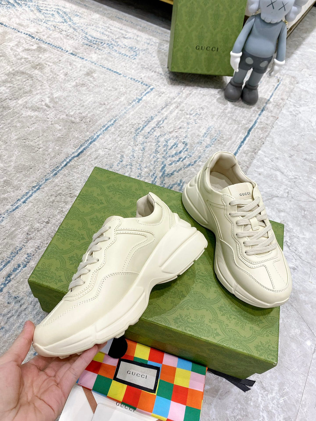 Cream unisex Gucci sneakers, front view with tennis-themed side emblem