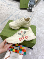 Cream unisex Gucci sneakers on green box, lace-up with tennis graphic