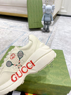 Close-up cream unisex Gucci sneaker with tennis graphic and red GUCCI logo