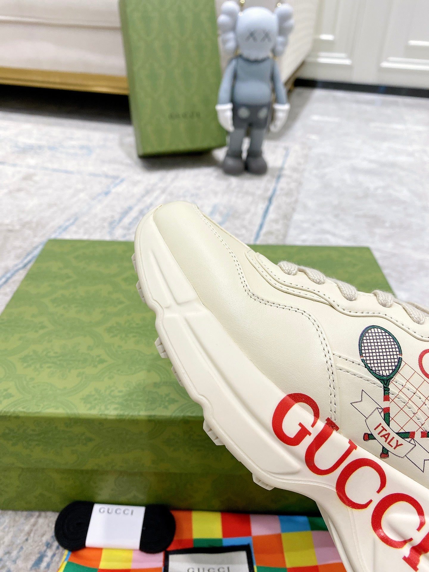 Cream unisex Gucci sneakers with side tennis graphic and red GUCCI lettering