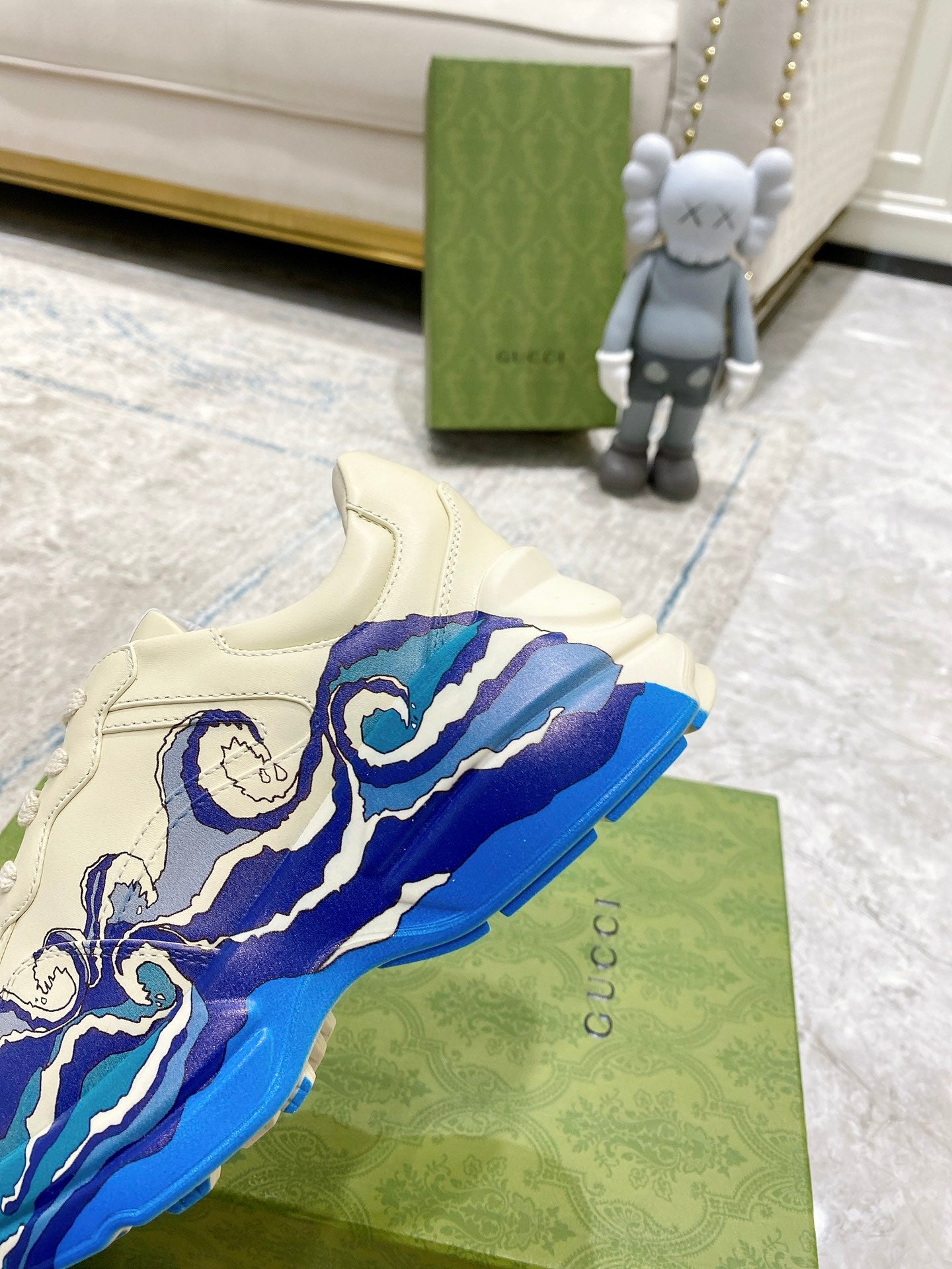 Close-up of white Gucci unisex sneaker with blue wave print and padded tongue