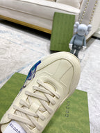 White Gucci unisex sneaker side view, lace-up with blue wave detail