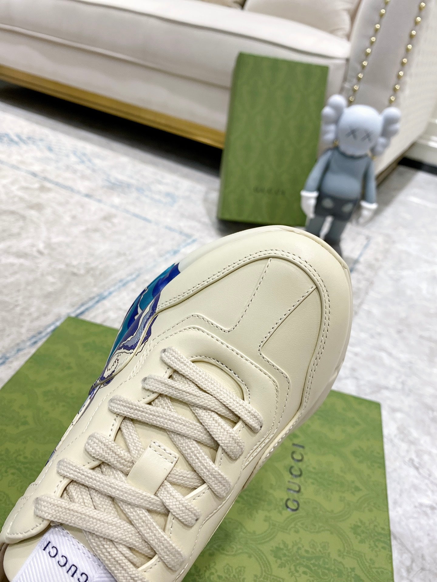 White Gucci unisex sneaker side view, lace-up with blue wave detail