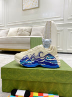White Gucci unisex low-top sneakers with bold blue wave overlay and laces