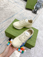 White Gucci unisex sneakers close-up, lace-up with blue wave accent on side