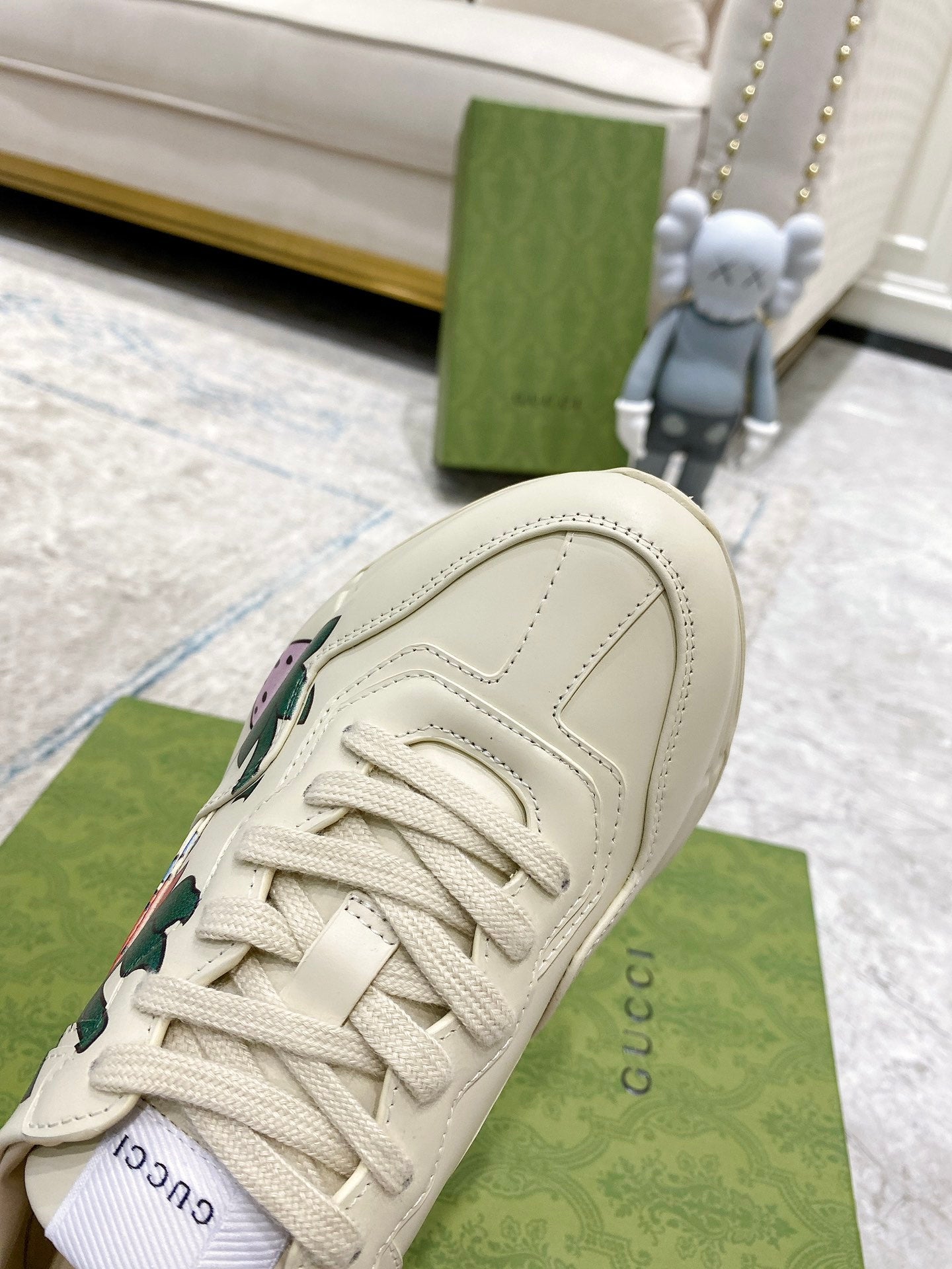 Gucci unisex sneakers close-up: cream leather toe with laces and stitched overlay panels.
