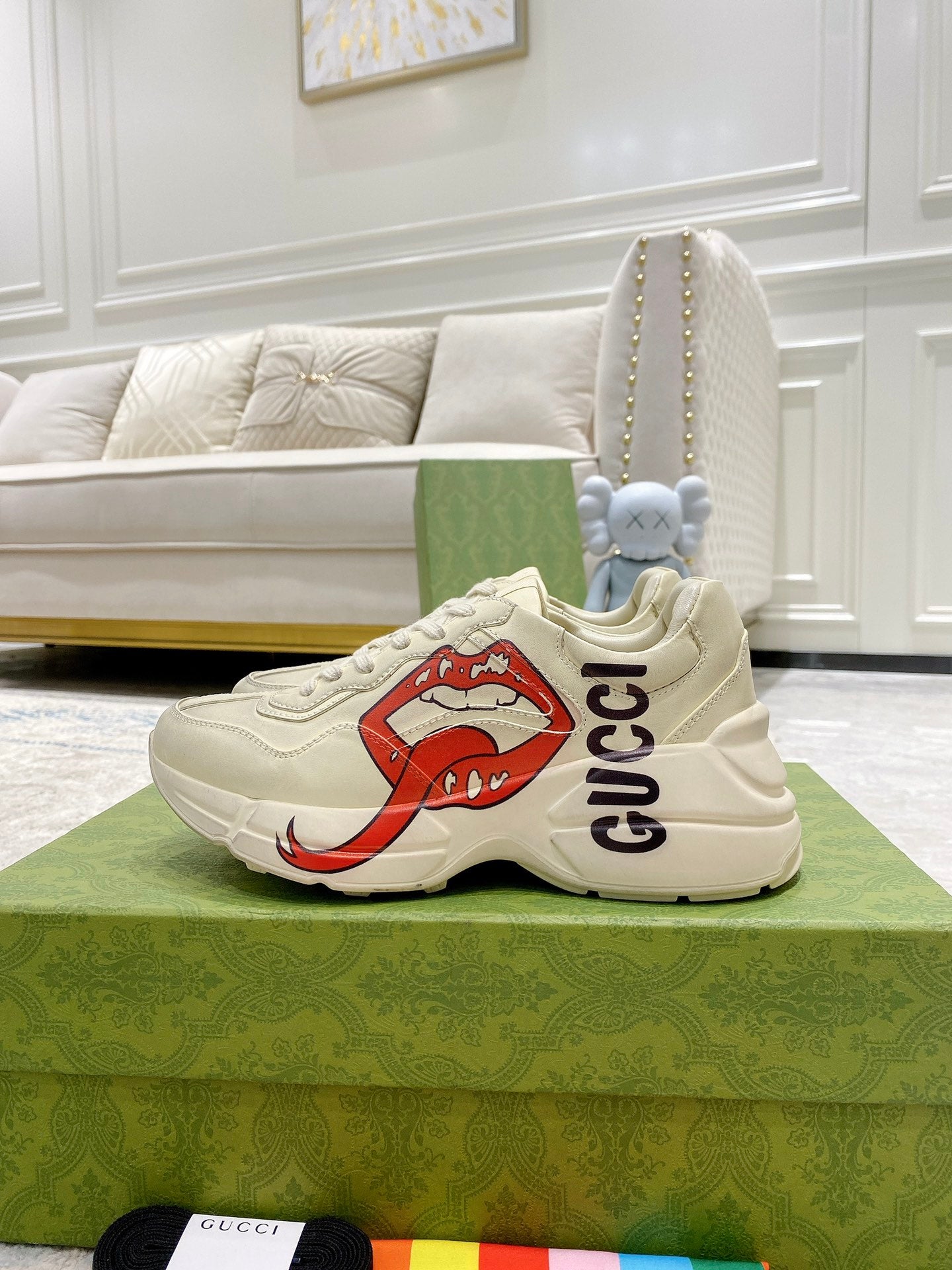 Light-cream Gucci unisex sneakers on green box, side view with red lip graphic