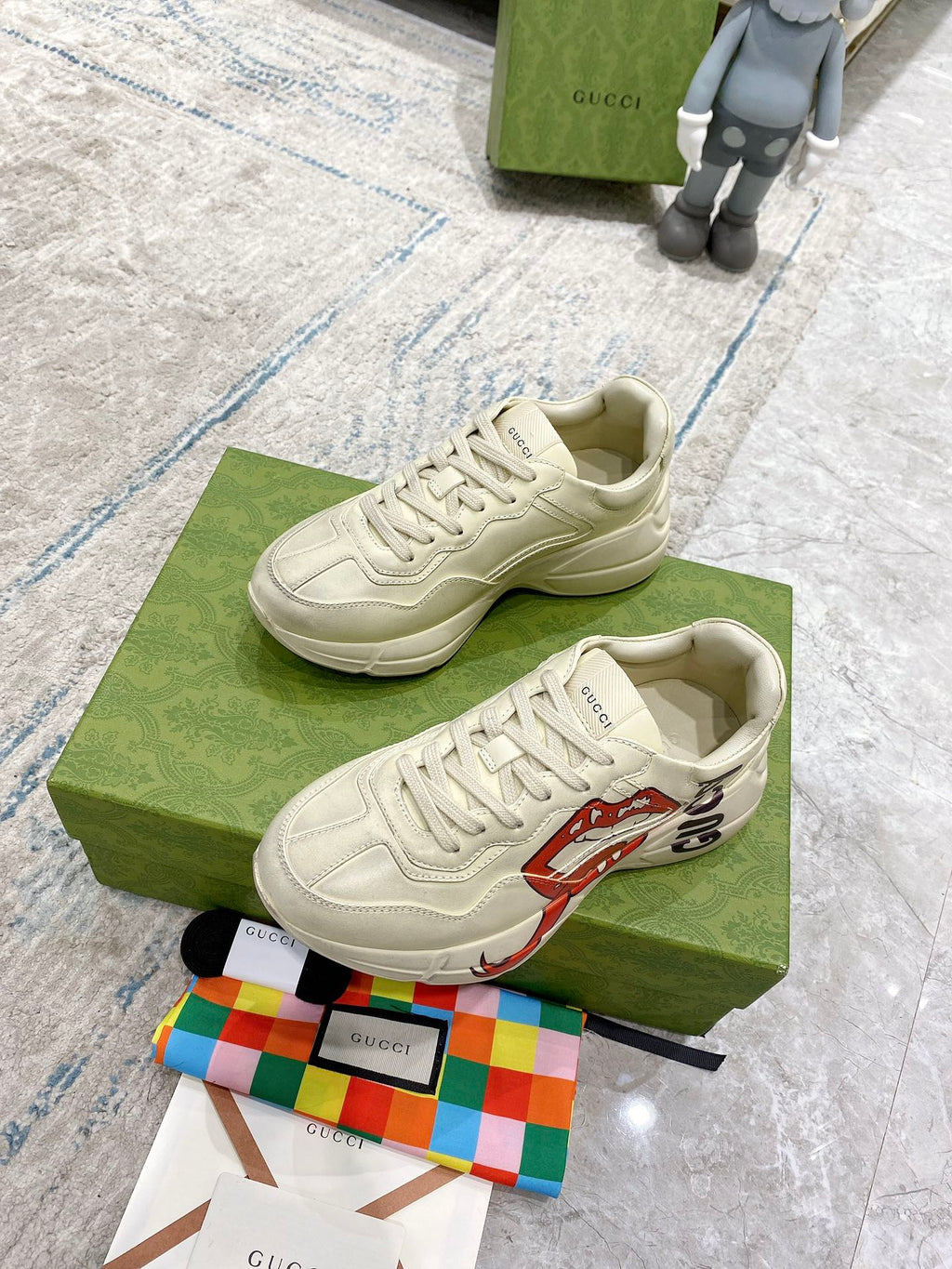 Light-cream Gucci unisex sneakers, angled view with red lip logo on side