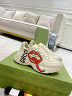 Light-cream Gucci unisex sneakers with red lip graphic and black Gucci logo detail