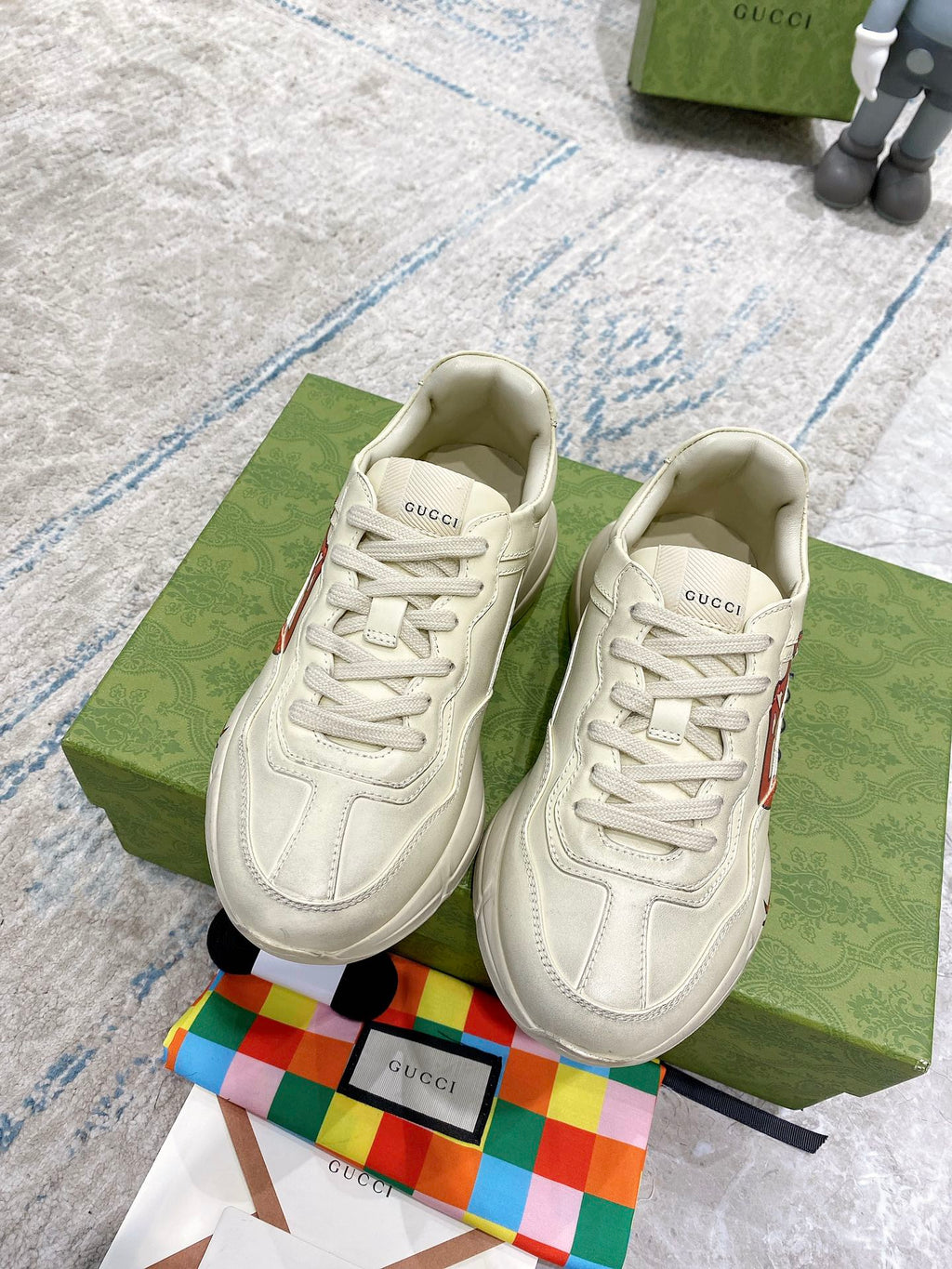 Light-cream Gucci unisex sneakers, front view, with lace-up design and red lip logo