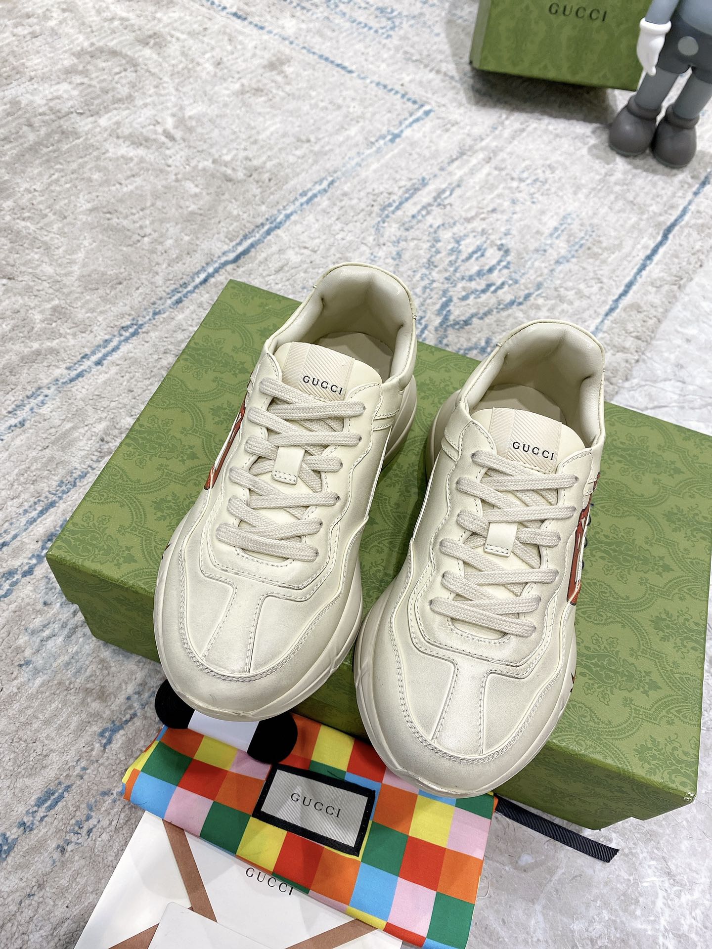 Light-cream Gucci unisex sneakers, front view, with lace-up design and red lip logo