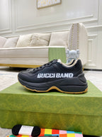 Gucci unisex sneakers, black pair on green box, side profile with GucciBand print