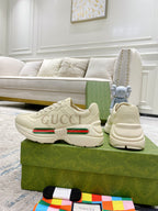 Cream Gucci sneakers pair on box, showing toe, lace-up, and green red stripe