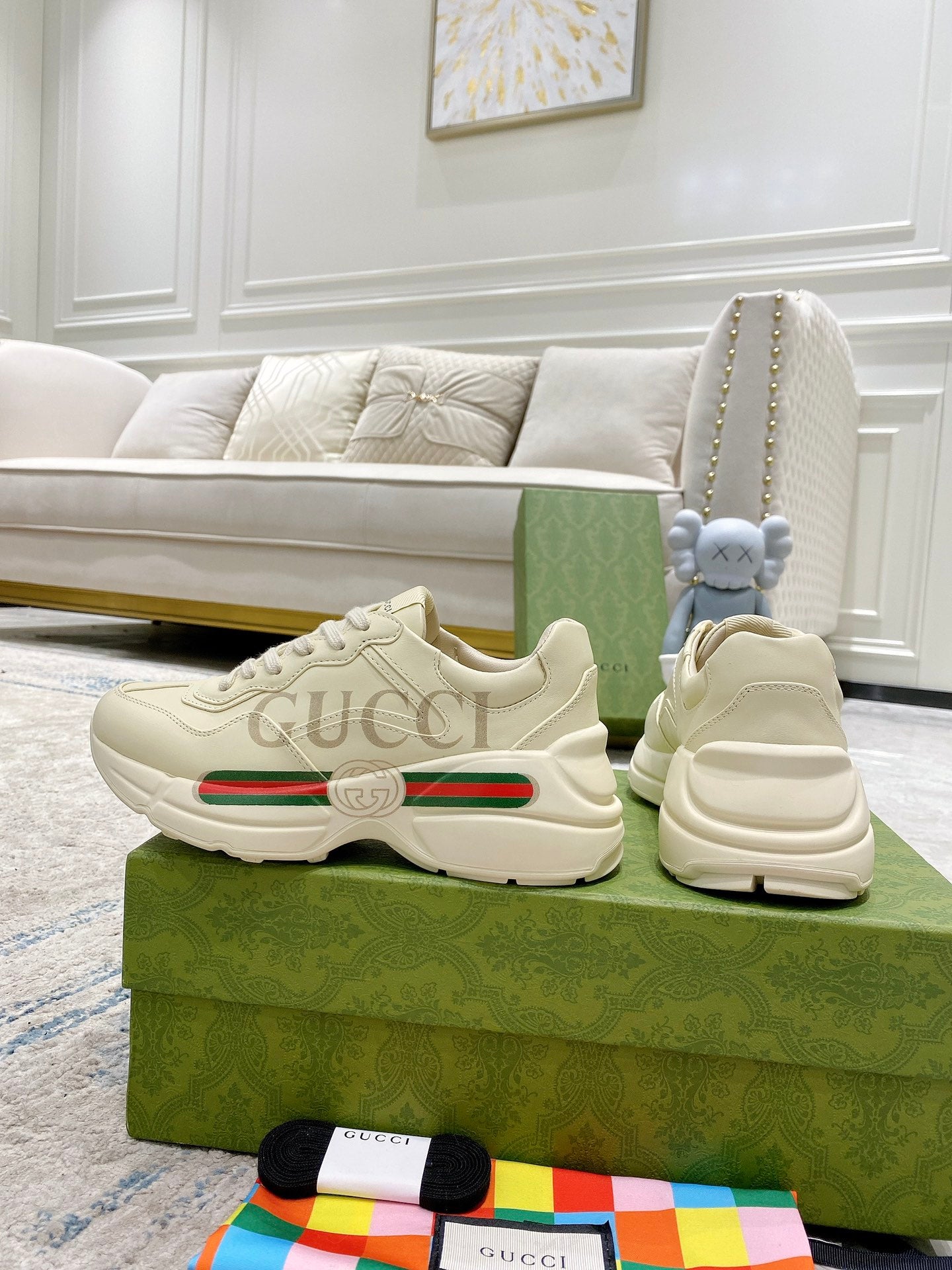 Cream Gucci sneakers pair on box, showing toe, lace-up, and green red stripe