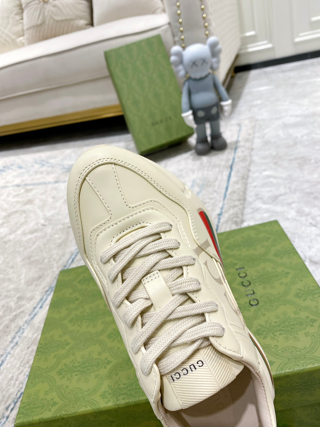 Cream Gucci sneaker upper close-up, lace-up front and side stripe panel