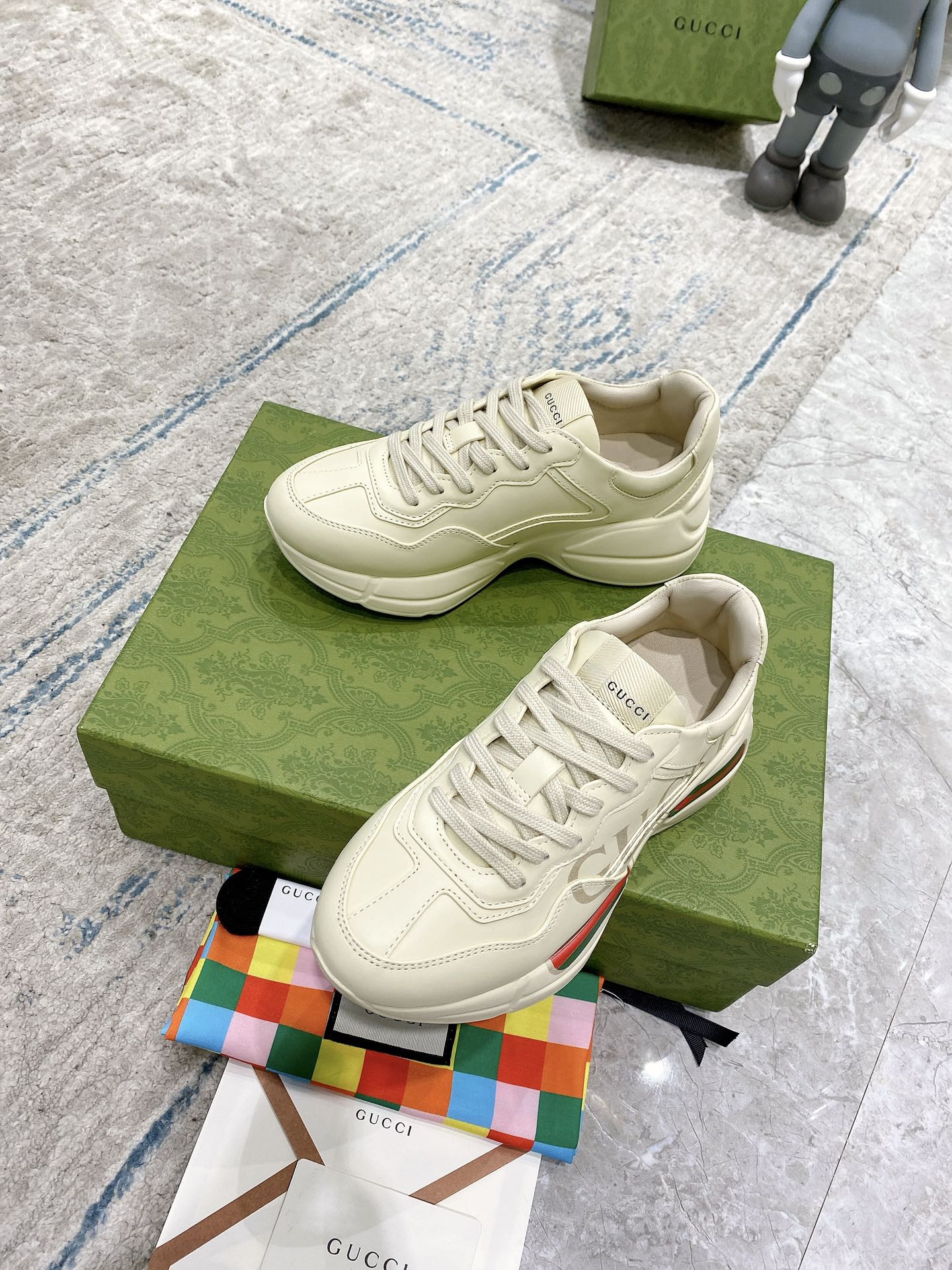 Cream Gucci sneakers on box, front view with lace-up and textured sole