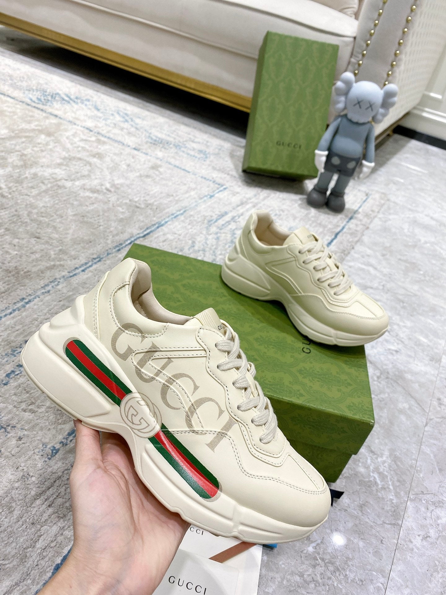 Cream Gucci running-style sneakers in hand, lace-up and green red side stripe