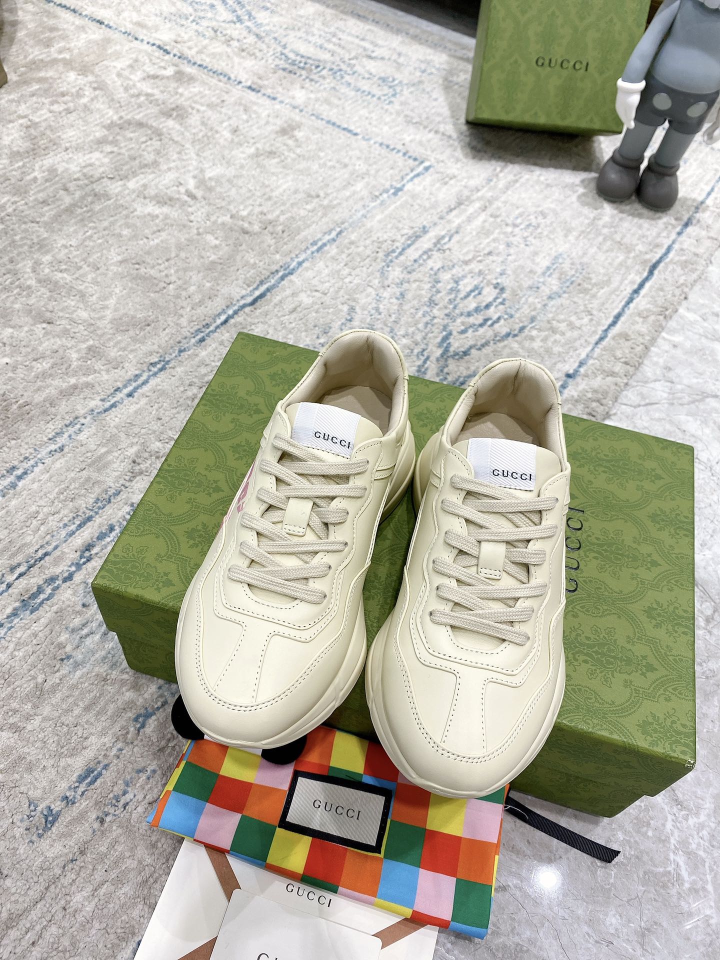 Cream Gucci lace-up sneakers with pink logo print and textured side panels.