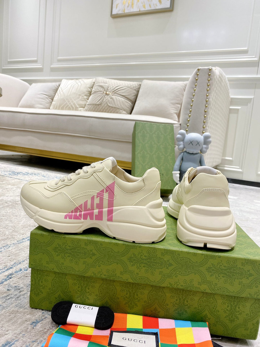 Cream Gucci sneakers with pink logo detail, stitched overlays and lace-up design.