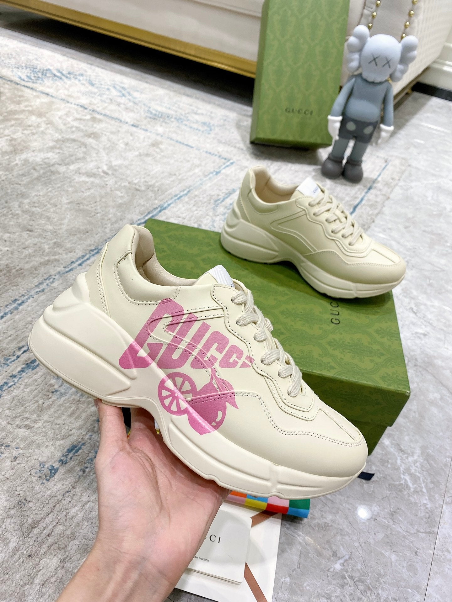 Cream Gucci sneakers with pink logo print, side view with lace-up and padded collar.