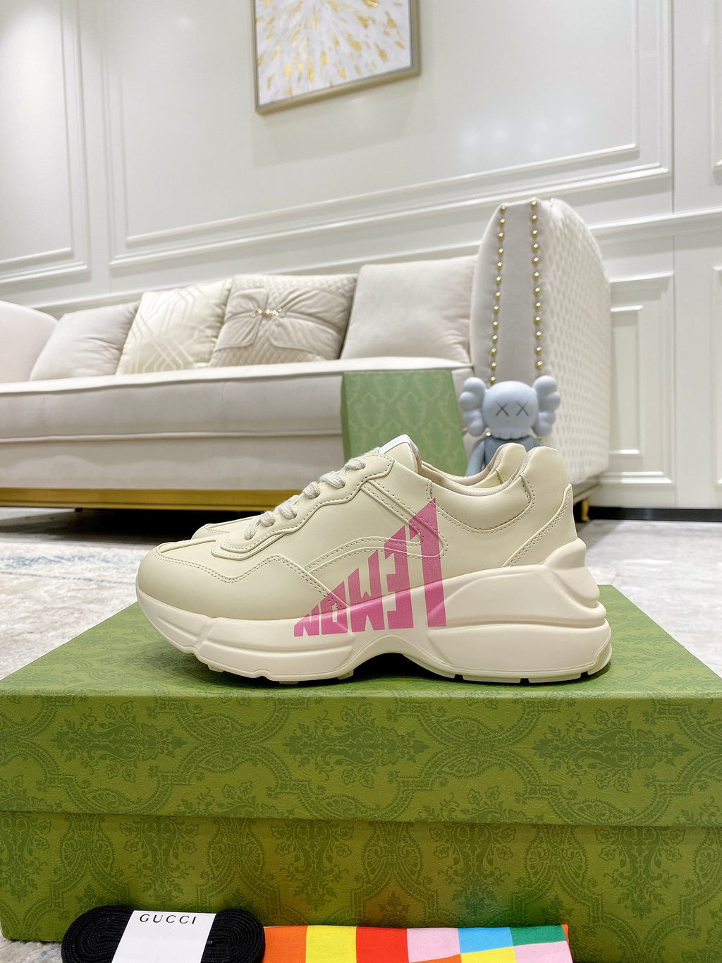 Pair of cream Gucci sneakers with pink logo, flat laces and rubber sole.
