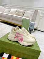 Cream Gucci sneakers with pink logo graphic, lace-up front and chunky sole.