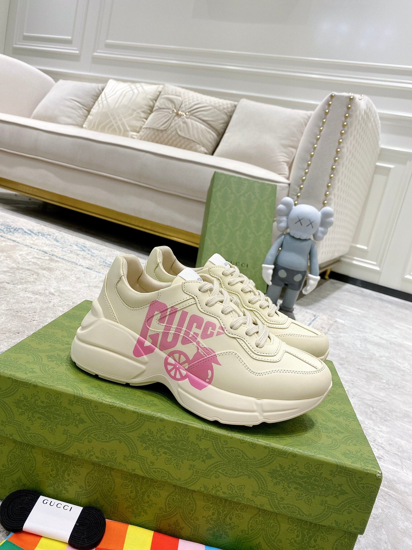 Cream Gucci sneakers with pink logo graphic, lace-up front and chunky sole.