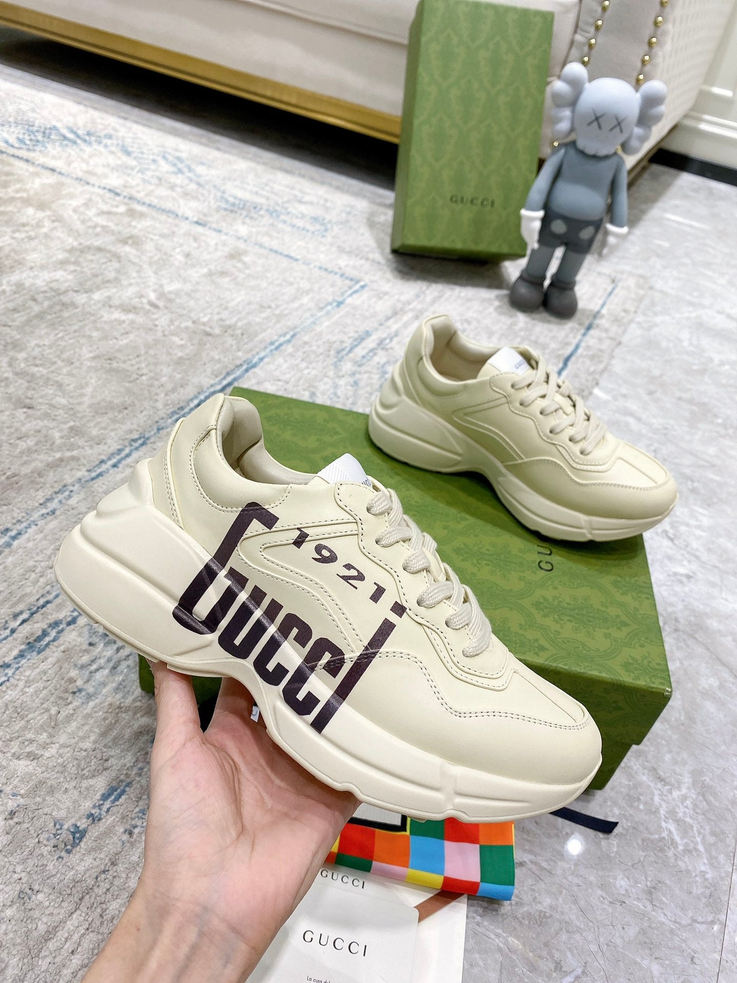 Gucci unisex sneakers in cream, angled view showing lace-up front and GUCCI 1921 side stripe