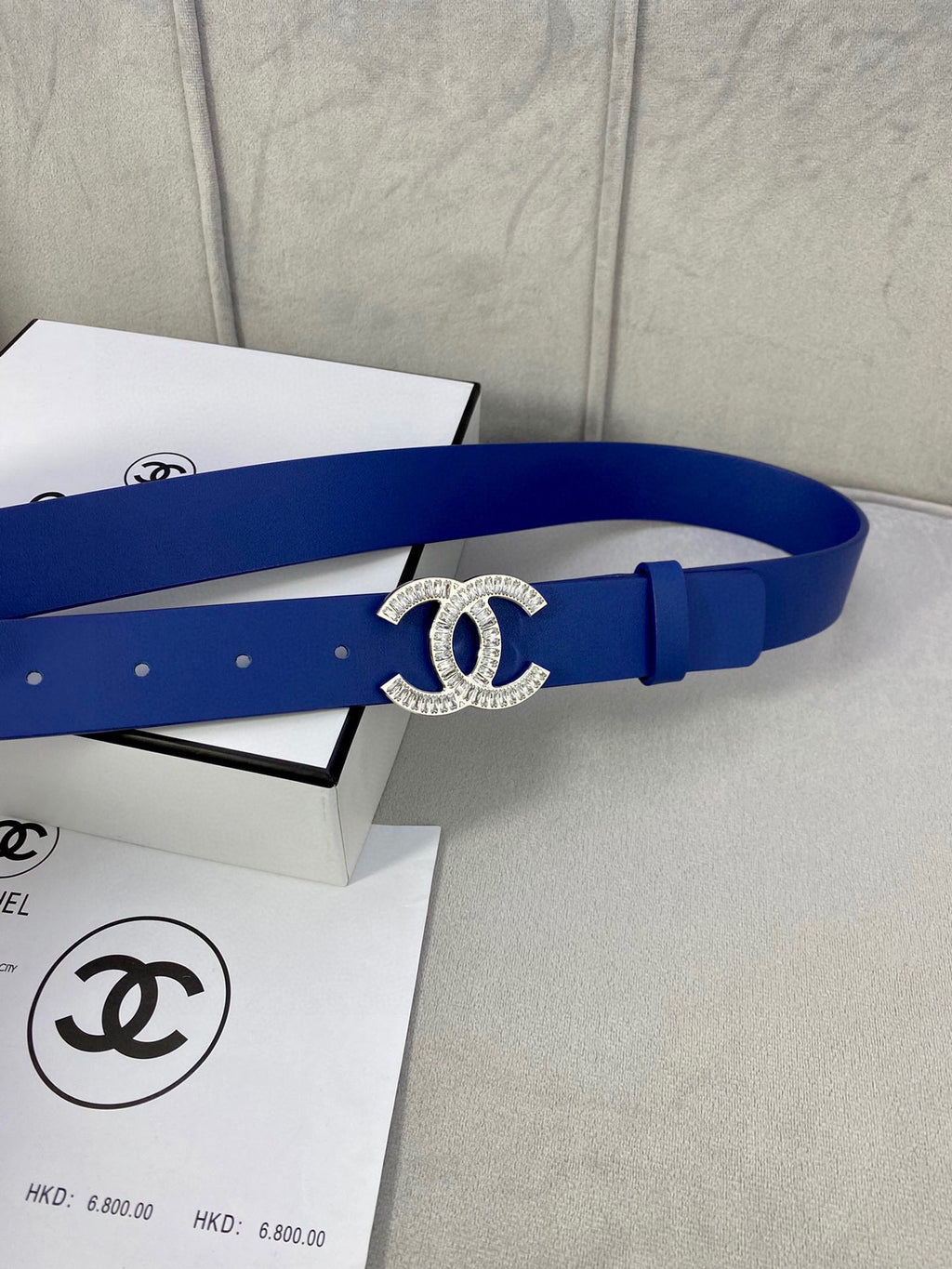 Blue leather belt with rhinestone CC logo buckle and adjustable holes, side view