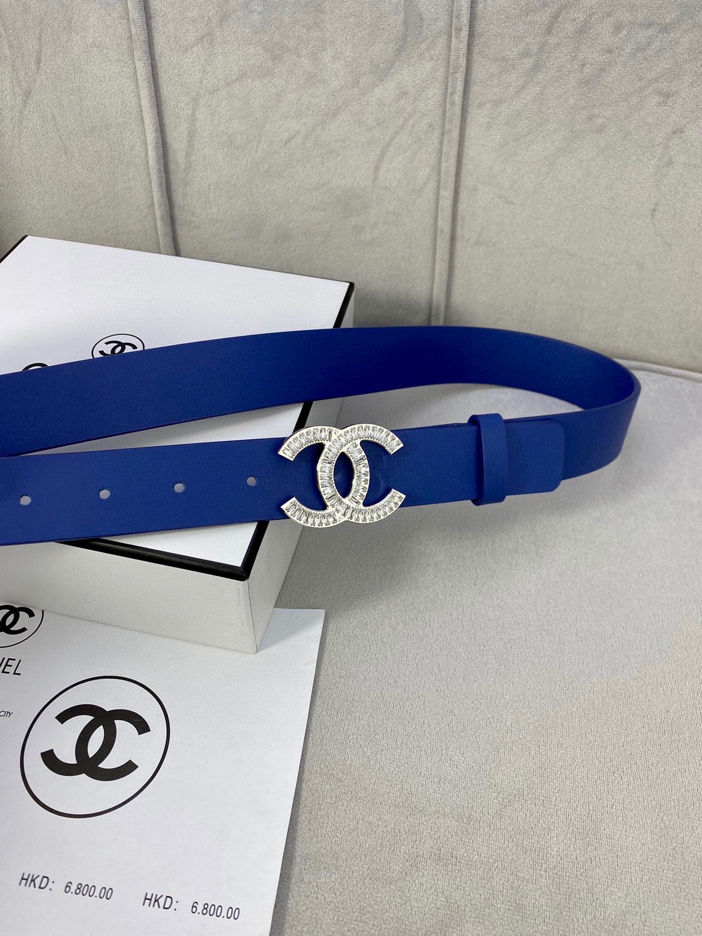 Blue leather belt with rhinestone CC logo buckle and adjustable holes, side view
