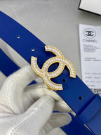 Blue leather belt close-up: gold-tone rhinestone CC buckle on blue strap