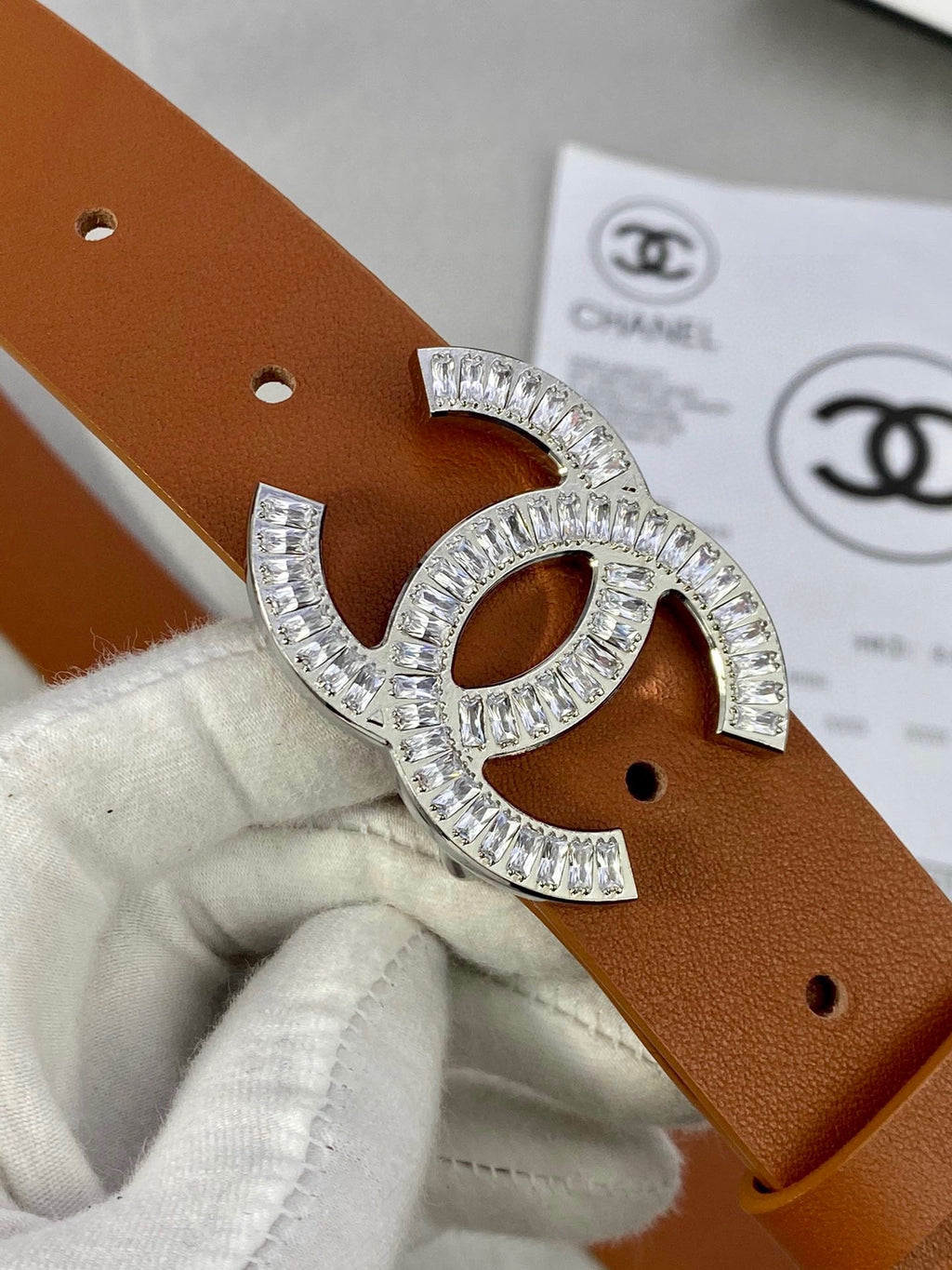 Brown leather Chanel belt close-up with gold-tone rhinestone CC buckle and side holes