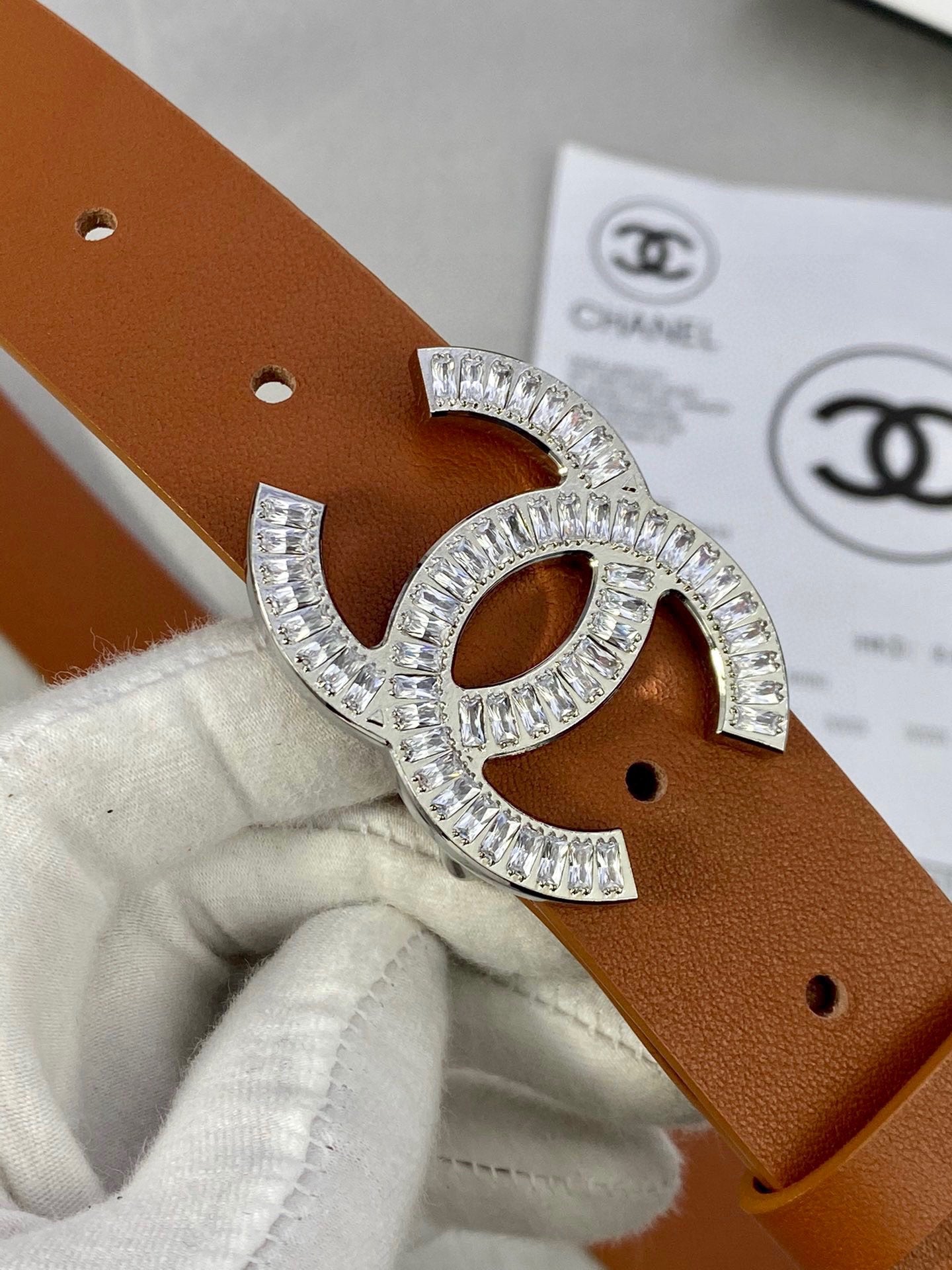Brown leather Chanel belt close-up with gold-tone rhinestone CC buckle and side holes