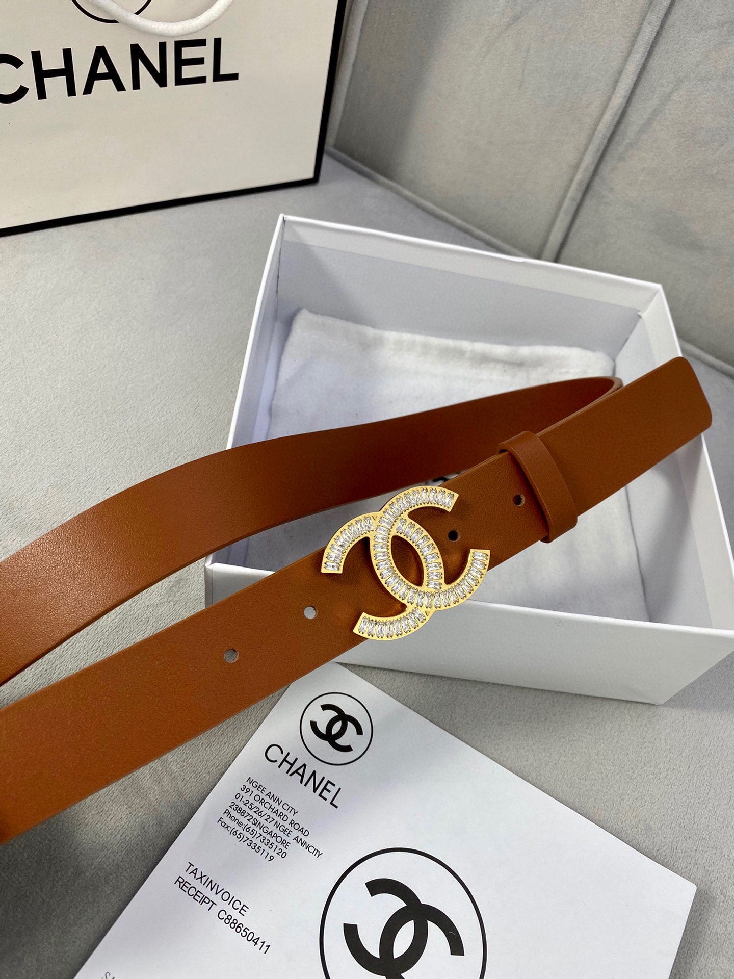 Brown leather Chanel belt with large gold-tone rhinestone CC buckle across the strap