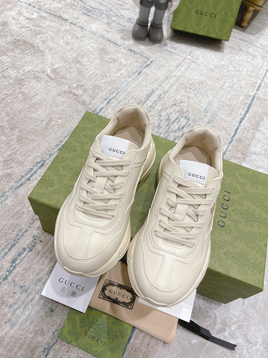 Pair of white Gucci unisex lace-up sneakers with side logo detail and padded tongue.