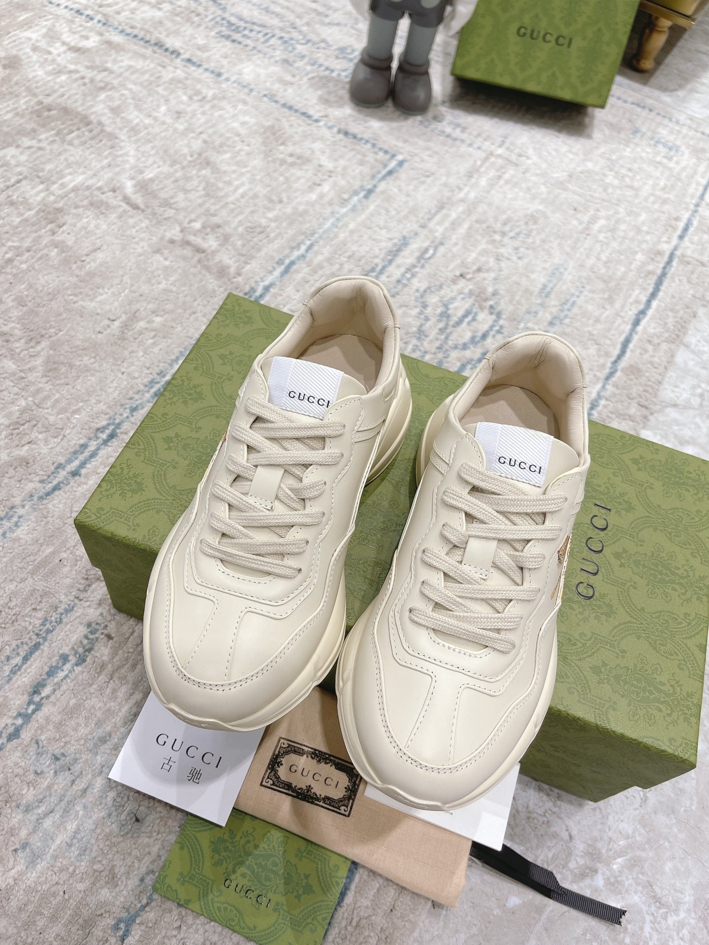 Pair of white Gucci unisex lace-up sneakers with side logo detail and padded tongue.