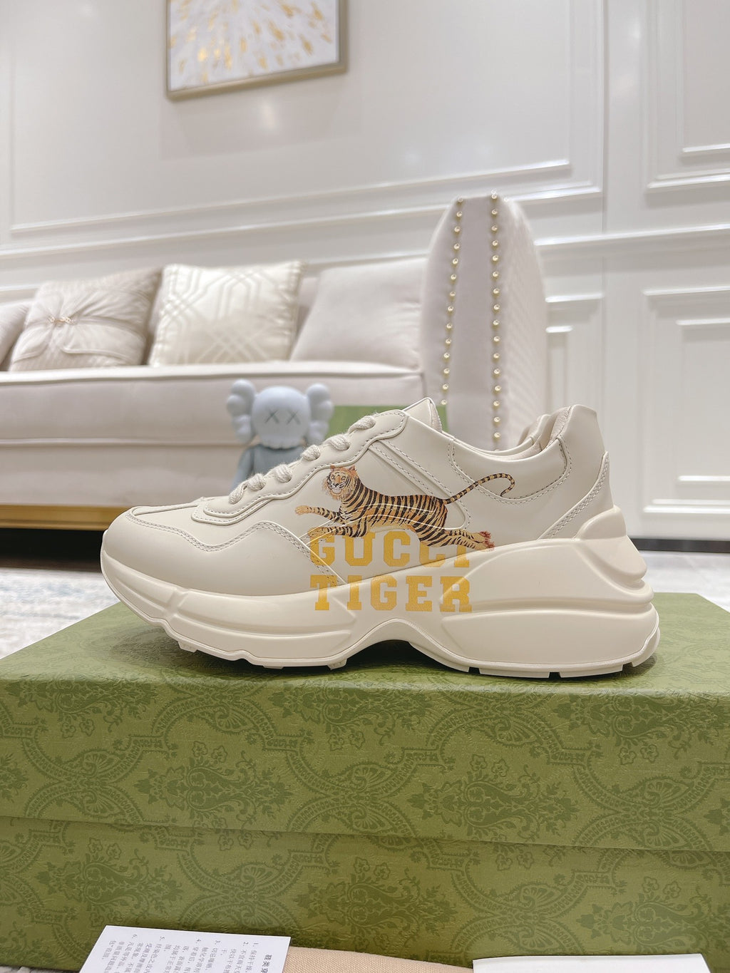 White Gucci unisex sneaker with tiger artwork and thick rubber sole, front view.