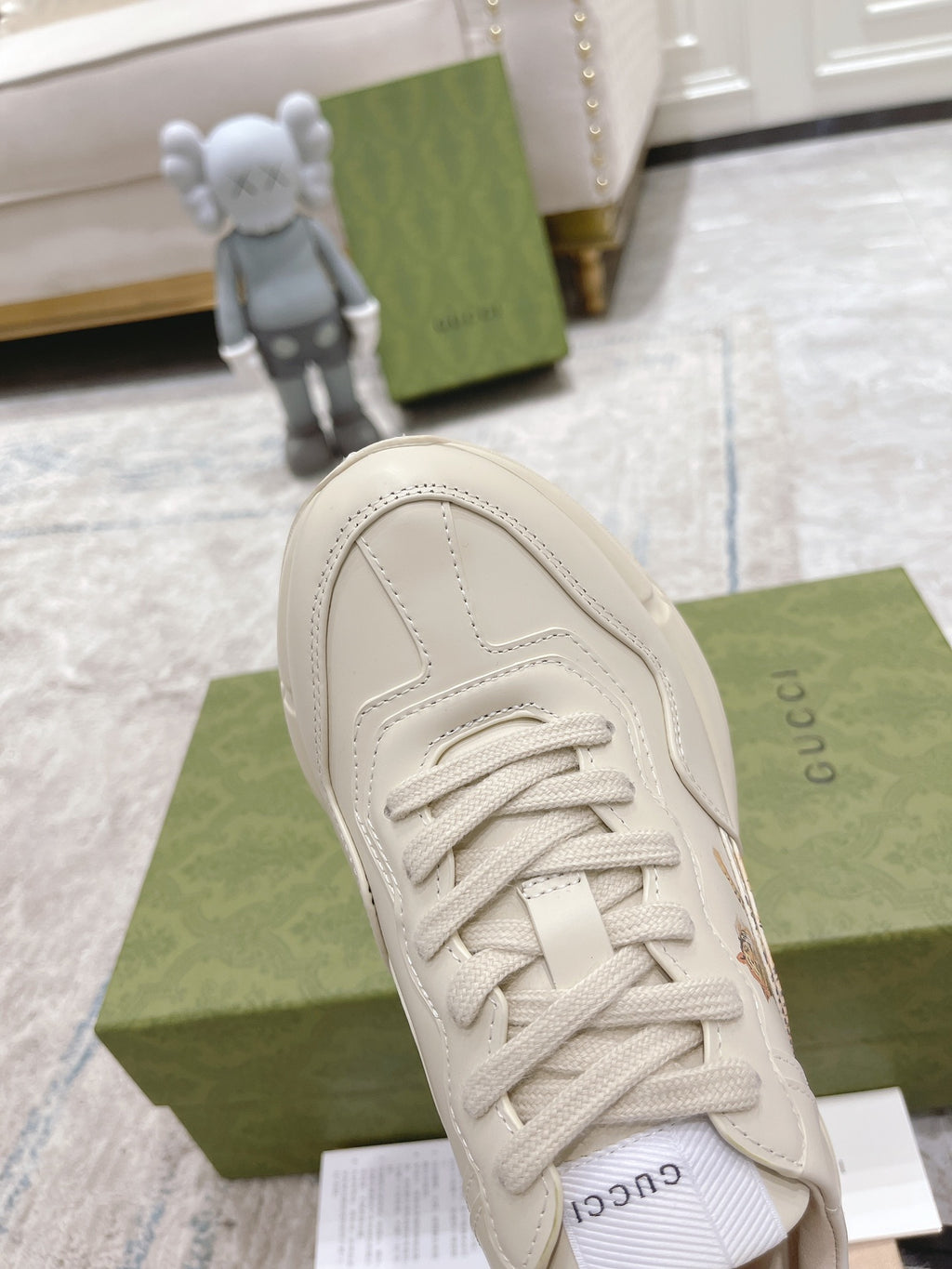 White Gucci unisex sneaker close-up of laces, rounded toe, and stitched upper.