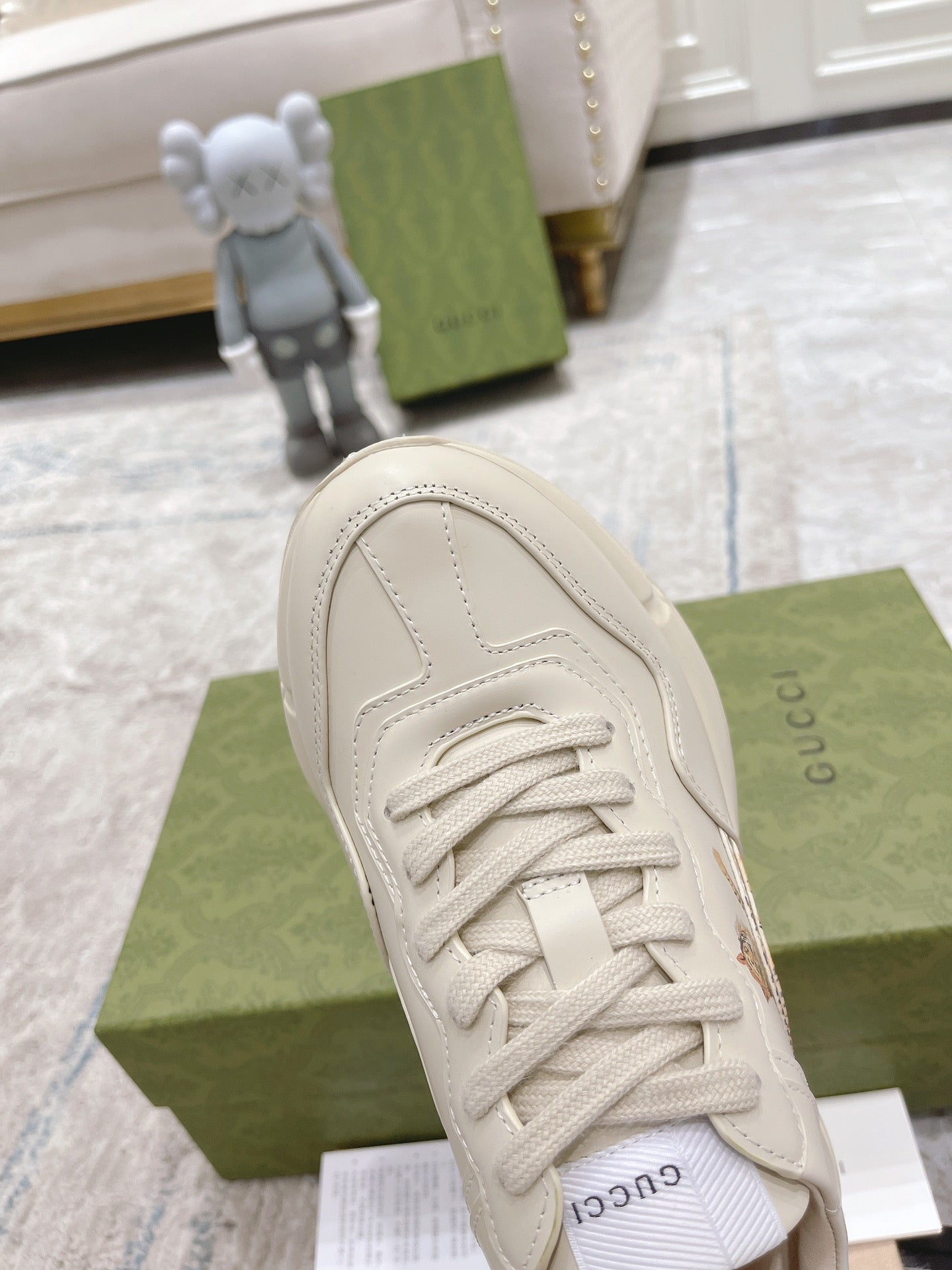 White Gucci unisex sneaker close-up of laces, rounded toe, and stitched upper.
