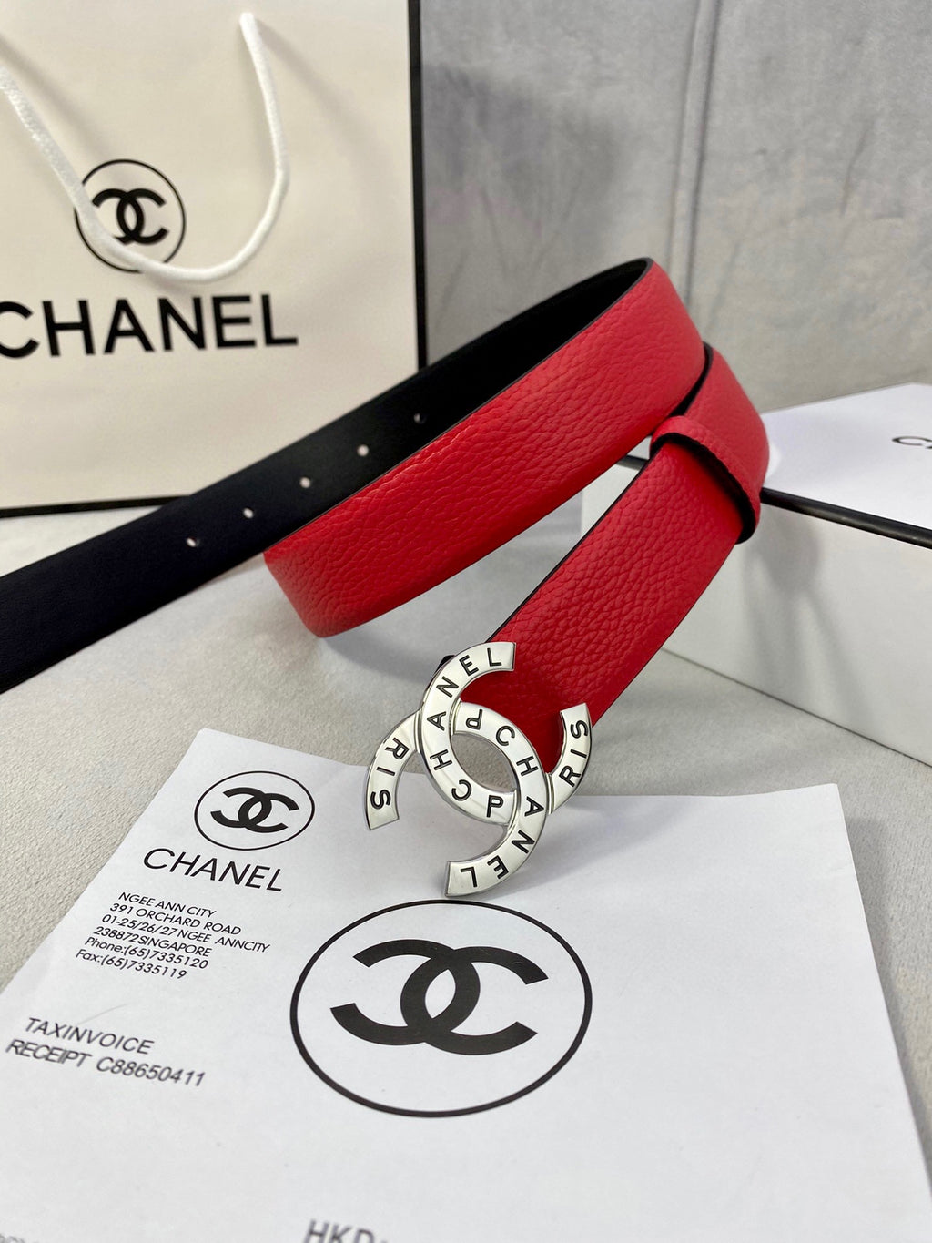 Chanel belt with red leather strap, gold CHANEL ring buckle, and visible hole details.