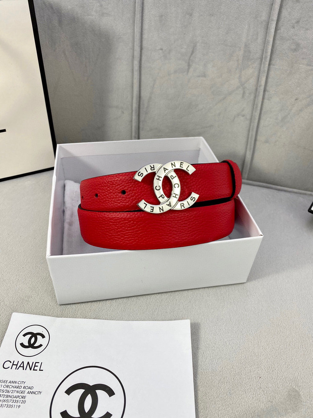 Chanel belt in white gift box: red textured leather strap with gold logo buckle.