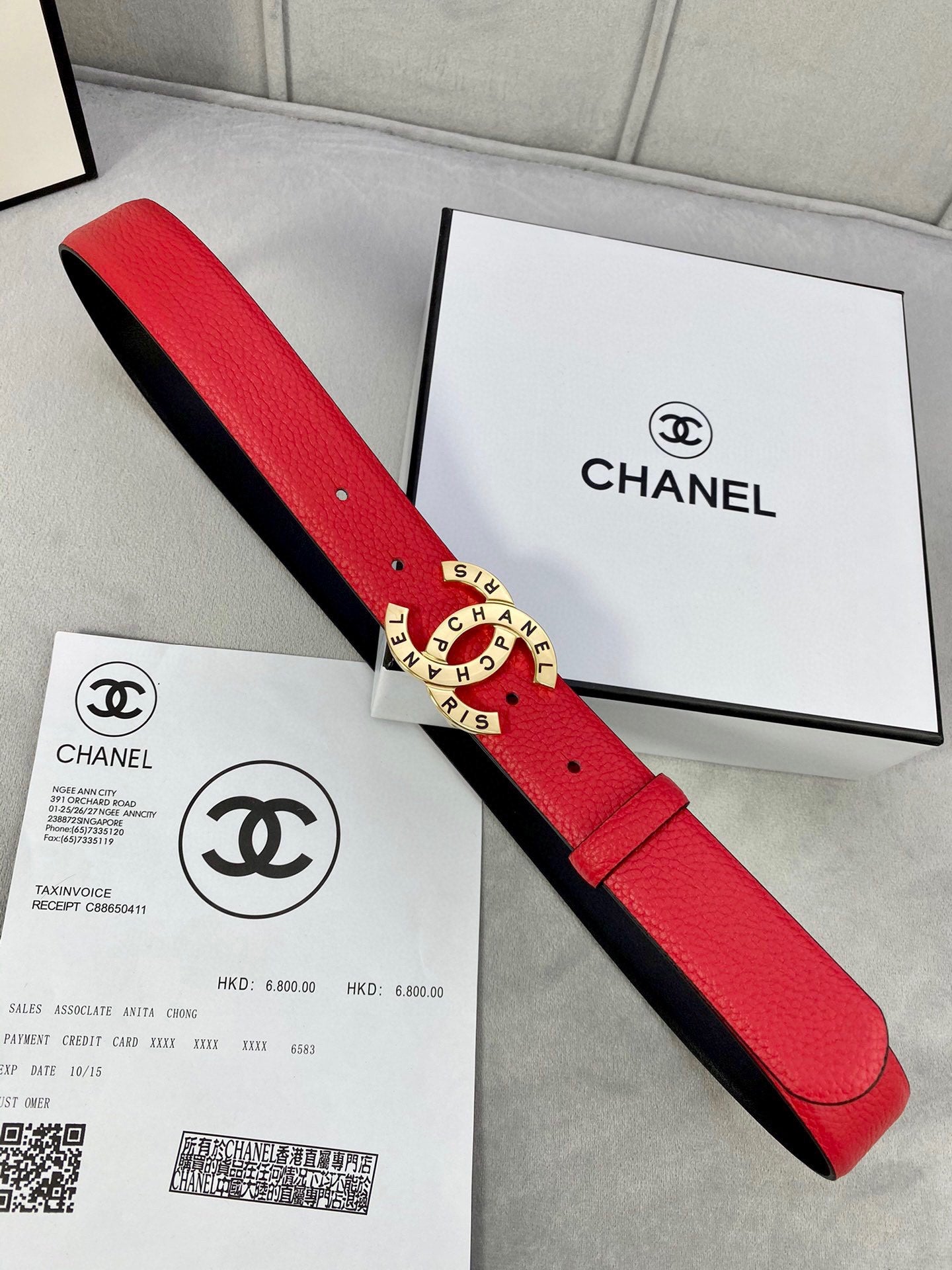 Chanel belt laid flat: red leather strap with gold CHANEL logo buckle and black inner backing.