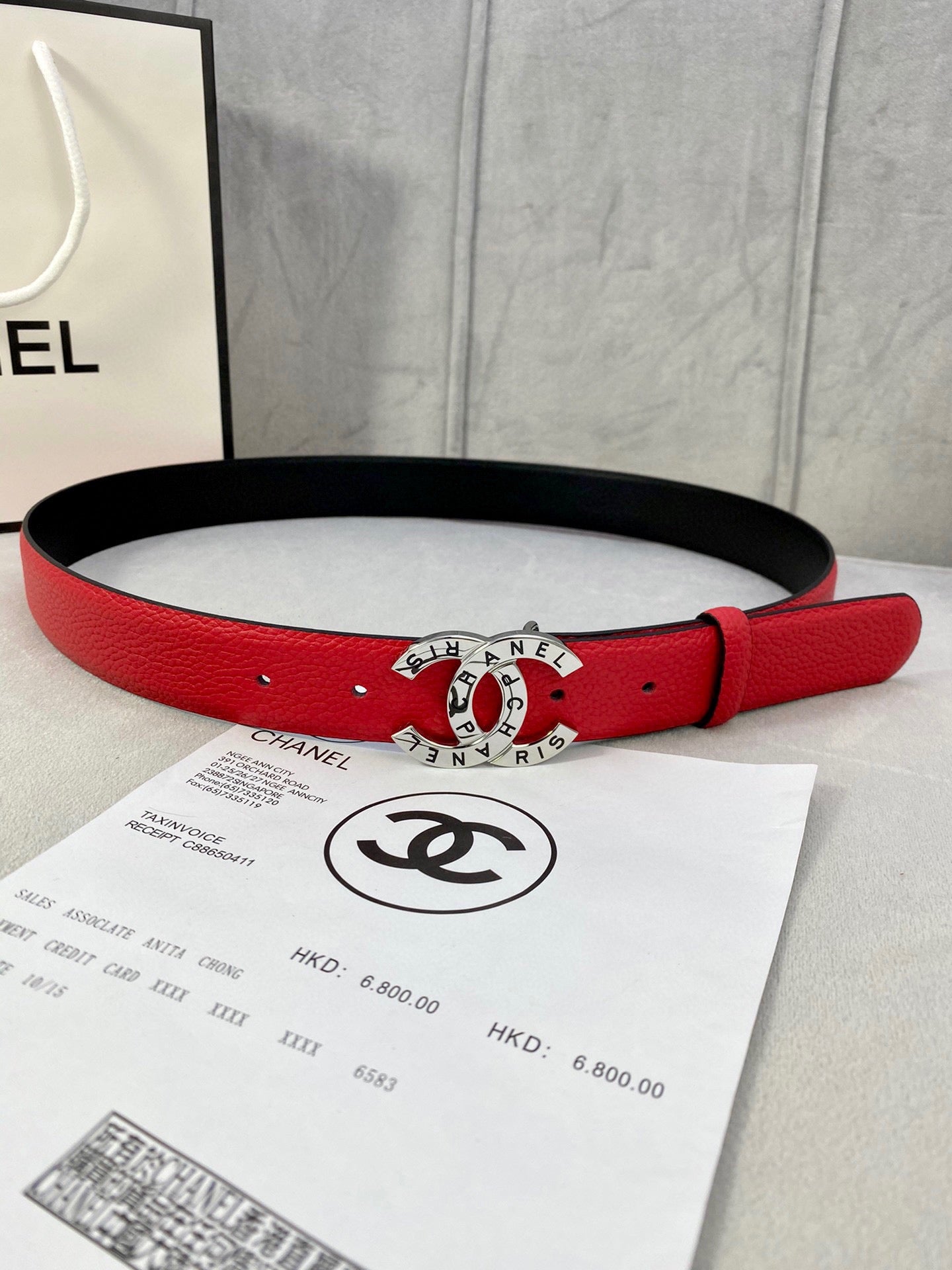 Chanel belt with red leather strap and gold logo buckle on a black underside.